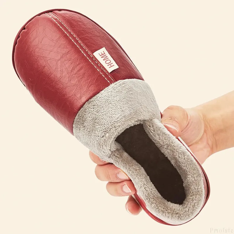 Pessoa segurando uma Pantufa Forrada de Couro para Inverno na cor vermelho, demonstrando a flexibilidade e conforto dos materiais
